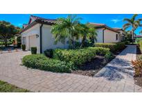 Well-maintained home features manicured landscaping with lush greenery and a brick paved walkway at 8279 Varenna Dr, Sarasota, FL 34231