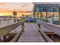 Covered boat dock with wooden walkway and seating area overlooking the waterfront at sunset at 903 20Th W Ave, Palmetto, FL 34221