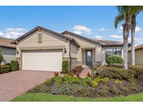 Single-story home with a two-car garage, landscaped yard, and brick paver driveway at 11136 Shearwater Ct, Sarasota, FL 34238