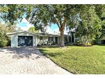 Charming single-story home featuring a large shade tree and a brick driveway with a two-car garage at 1705 Shoreland Dr, Sarasota, FL 34239