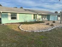 Light teal ranch house with a gray roof, landscaping, and a paved driveway at 211 84Th St, Holmes Beach, FL 34217