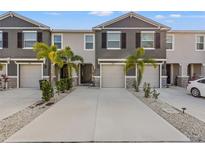 Three-unit townhome building with gray siding, two-car garages, and palm trees at 2850 Midnight Pearl Dr, Sarasota, FL 34240