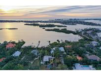 Aerial view of waterfront home with lush landscaping and sunset at 3950 Red Rock Way, Sarasota, FL 34231