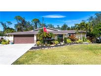 Single-story home with brown garage door, landscaping, and large yard at 4517 N Lake Dr, Sarasota, FL 34232