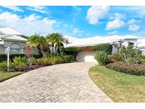 House exterior featuring a brick driveway, lush landscaping, and a two-car garage at 6790 Paseo Castille, Sarasota, FL 34238