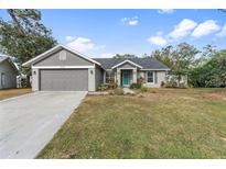 Newly renovated gray house with a teal front door and landscaped yard at 7117 Queen Palm Cir, Sarasota, FL 34243