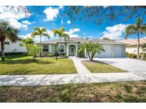 Charming single-story home with a well-manicured lawn, a three-car garage, and beautiful palm trees at 1069 Harbour Cape Pl, Punta Gorda, FL 33983