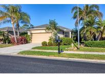 Charming single-story home featuring a beige exterior, well-manicured landscaping, and a two-car garage at 11938 Tempest Harbor Loop, Venice, FL 34292