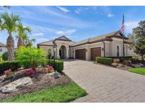 Elegant single-story home featuring a paver driveway, lush landscaping, and a three-car garage at 14208 Woodhall Pl, Bradenton, FL 34202