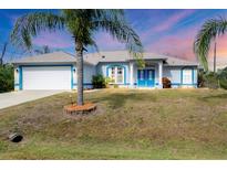 Charming single-story home with a two-car garage, vibrant blue trim and beautiful tropical landscaping at 2926 Sultan Ct, North Port, FL 34286