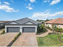 Two-car garage, paver driveway, landscaped walkway, and attractive exterior at 3016 Formia Ct, Bradenton, FL 34211