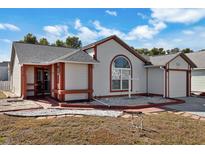 Single-story house with a landscaped lawn, red-trimmed exterior, and a two-car garage at 3815 42Nd W Ave, Bradenton, FL 34205