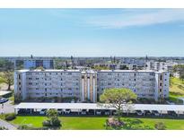 A view of the Condo building with covered parking, manicured lawn, and landscaping at 3880 Ironwood Ln # 408E, Bradenton, FL 34209