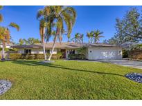 Single-story home with a tile roof, landscaped lawn, and palm trees at 419 Partridge Cir, Sarasota, FL 34236