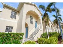 Tan two-story condo building with blue door, white stairs, and landscaping at 4215 Breezeway Blvd # 2420, Sarasota, FL 34238