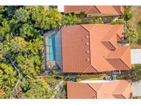 Aerial view of a home with a red tile roof, pool and tropical landscaping at 5827 Beaurivage Ave, Sarasota, FL 34243