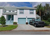 Two-story condo with teal accents, two-car garage, and a truck parked in the driveway at 6589 Fairway Gardens Dr, Bradenton, FL 34203