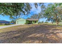 Newly built home with green exterior, two-car garage, and landscaped yard at 7930 Verna Bethany Rd, Myakka City, FL 34251