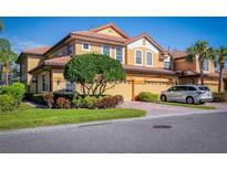 Tan two-story home with two-car garage, lush landscaping, and a paved driveway at 8368 Miramar Way # 21, Lakewood Ranch, FL 34202