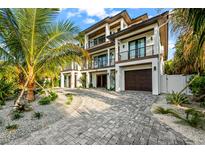 Luxury home with palm trees, driveway, and attached garage at 107 Maple Ave, Anna Maria, FL 34216