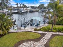 Waterfront property featuring a covered boat dock with boat lift, lush landscaping and winding brick pavers at 121 Holly Ave, Sarasota, FL 34243