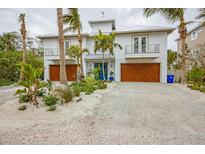 Two-story home with double wooden garage doors and landscaped front yard at 238 Oak Ave, Anna Maria, FL 34216