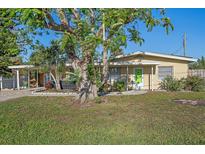 Charming single-story home featuring a green front door, mature trees and a well-maintained lawn at 5713 Saint Louis Ave, Sarasota, FL 34233