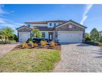 Two-story house with stone accents, three-car garage, and landscaped yard at 6868 Wild Lake Ter, Bradenton, FL 34212