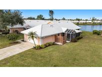 Exterior view of charming villa with lake access, lush landscaping, and attached garage at 713 Harrington Lake N Dr # 18, Venice, FL 34293