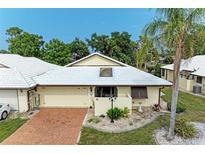 An aerial view of a charming villa with a brick driveway and lush landscaping at 96 Drifting Sands Dr, Venice, FL 34293