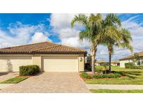 Two-car garage, tile roof, and landscaped yard with palm trees at 12563 Felice Dr, Venice, FL 34293