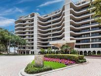 Elegant condo building featuring rounded balconies, lush landscaping, and a circular driveway at 415 L Ambiance Dr # C404, Longboat Key, FL 34228