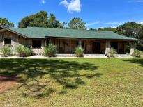 Ranch style home with green roof, wood siding, and spacious lawn at 5134 241St E St, Myakka City, FL 34251