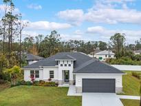White modern house with gray roof and dark gray garage door, landscaped lawn at 2219 Greenley Rd, North Port, FL 34286