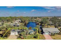 Beautiful waterfront home with lush landscaping, mature palm trees, and brick driveway on a sunny day at 309 South Dr, Nokomis, FL 34275