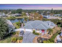 Aerial view of single-Gathering home with a gray roof, red door, and landscaped yard; located near a lake at 8348 9Th Avenue Nw Ter, Bradenton, FL 34209