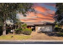 Single-story home with stone accents and a two-car garage, showcasing a beautiful sunset at 917 S Doral Ln, Venice, FL 34293