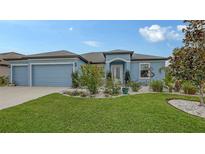 Beautiful light blue house with a 3-car garage and nicely landscaped front yard at 12607 Wheatgrass Ct, Parrish, FL 34219