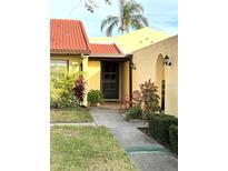 Inviting front entry with red bench and lush landscaping at 1331 57Th W St # 1331, Bradenton, FL 34209