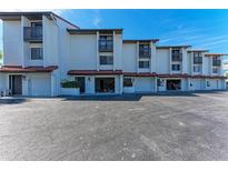 Front view of a light-colored multi-unit building with attached garages and ample parking at 6840 Midnight Pass Rd # 6840, Sarasota, FL 34242