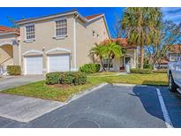 Tan two-story condo with two-car garage, lush landscaping, and palm trees at 7133 Cedar Hollow Cir # 22-102, Bradenton, FL 34203