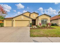 Charming single-story home with a three-car garage, manicured lawn, and colorful landscaping at 9214 Raes Creek Pl, Palmetto, FL 34221