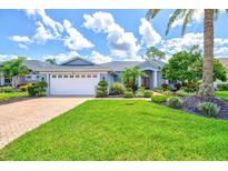 Charming home with a well-manicured lawn, lush landscaping, and a brick-paved driveway at 7453 Featherstone Blvd, Sarasota, FL 34238