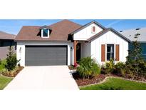 White farmhouse exterior with brown roof, landscaping, and a two-car garage at 8219 Abalone Loop, Parrish, FL 34219