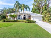 Single-story home with tile roof, palm trees, and a well-manicured lawn at 8624 Woodbriar Dr, Sarasota, FL 34238