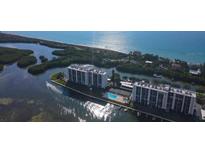 Aerial view of waterfront property with two buildings, pool, and boat docks at 9397 Midnight Pass Rd # 603, Sarasota, FL 34242