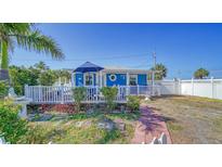 Charming blue cottage with a deck, white fence, and landscaped yard at 111 9Th N St, Bradenton Beach, FL 34217