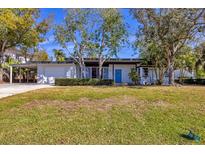 Mid-century modern home with carport, mature landscaping, and spacious lawn at 1509 Flower Dr, Sarasota, FL 34239