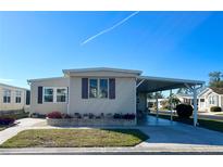 Tan single-wide manufactured home with covered carport at 3214 Pink Oak Ter, Sarasota, FL 34237