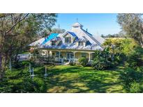 Charming home with a large, green lawn and a welcoming front porch with ornate railings and lush landscaping at 4946 Hubner Cir Cir, Sarasota, FL 34241